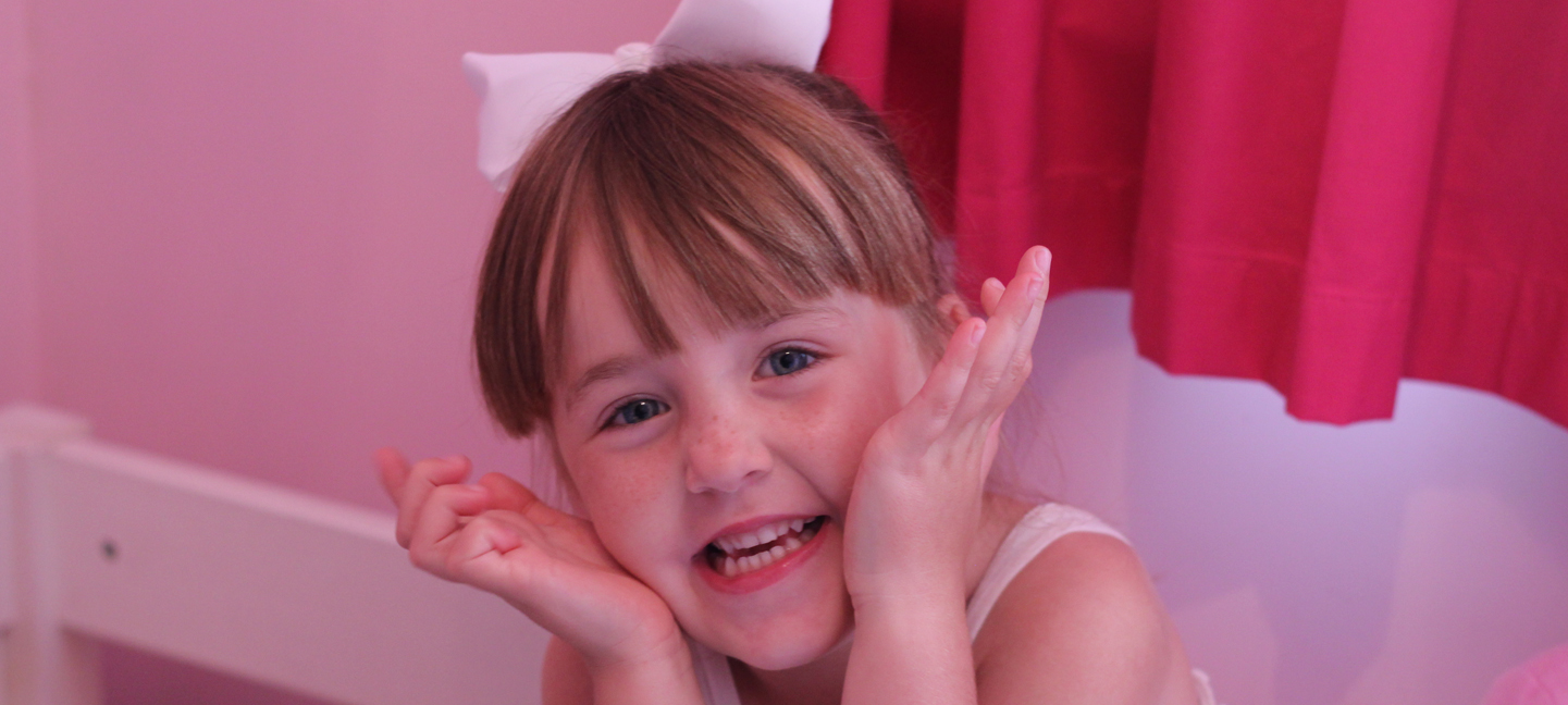 Little girl smiling in her pink bedroom