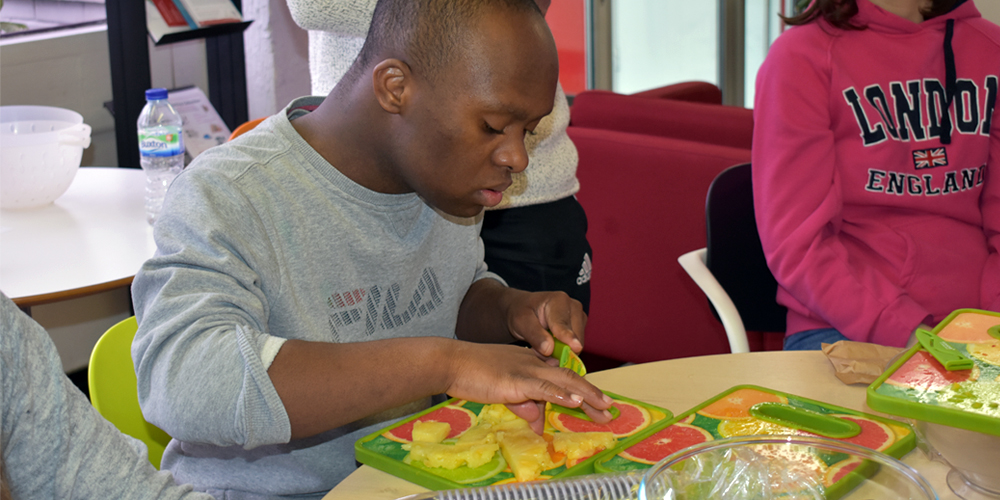 Disabled boy cutting fruit for snacks