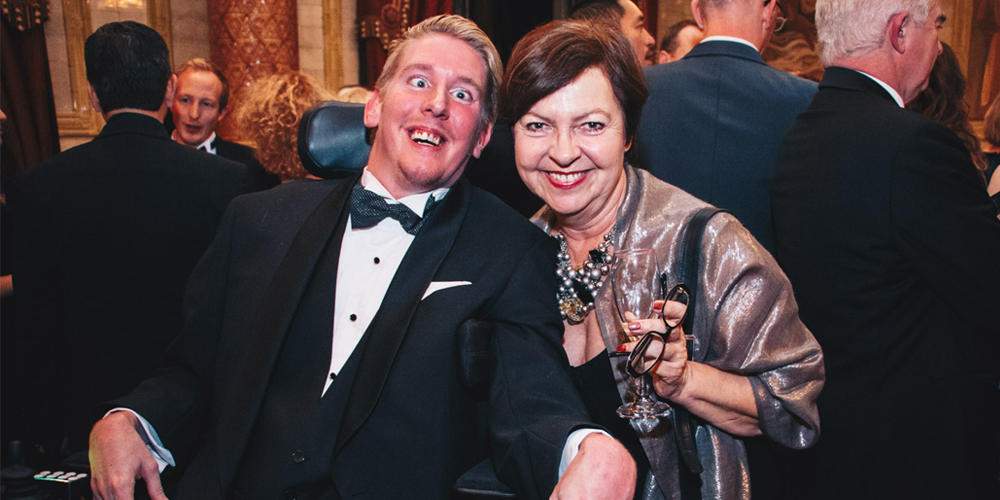 Man in a powerchair and a woman at a gala dinner