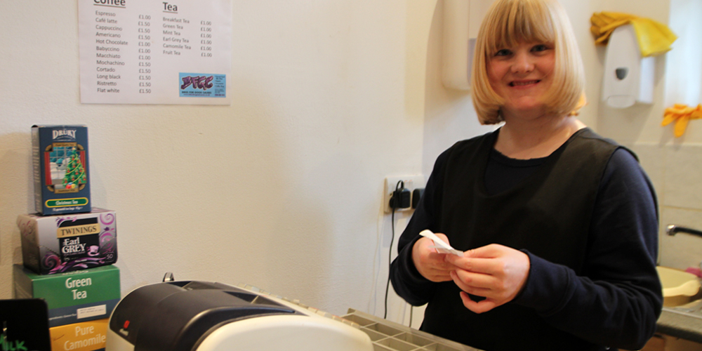 Girl with learning disabilities smiling while putting money in the till