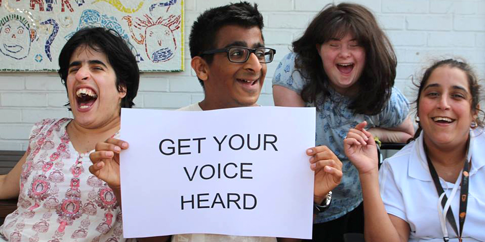 Group of young people with learning disabilities holding a sign saying 'get your voice heard'