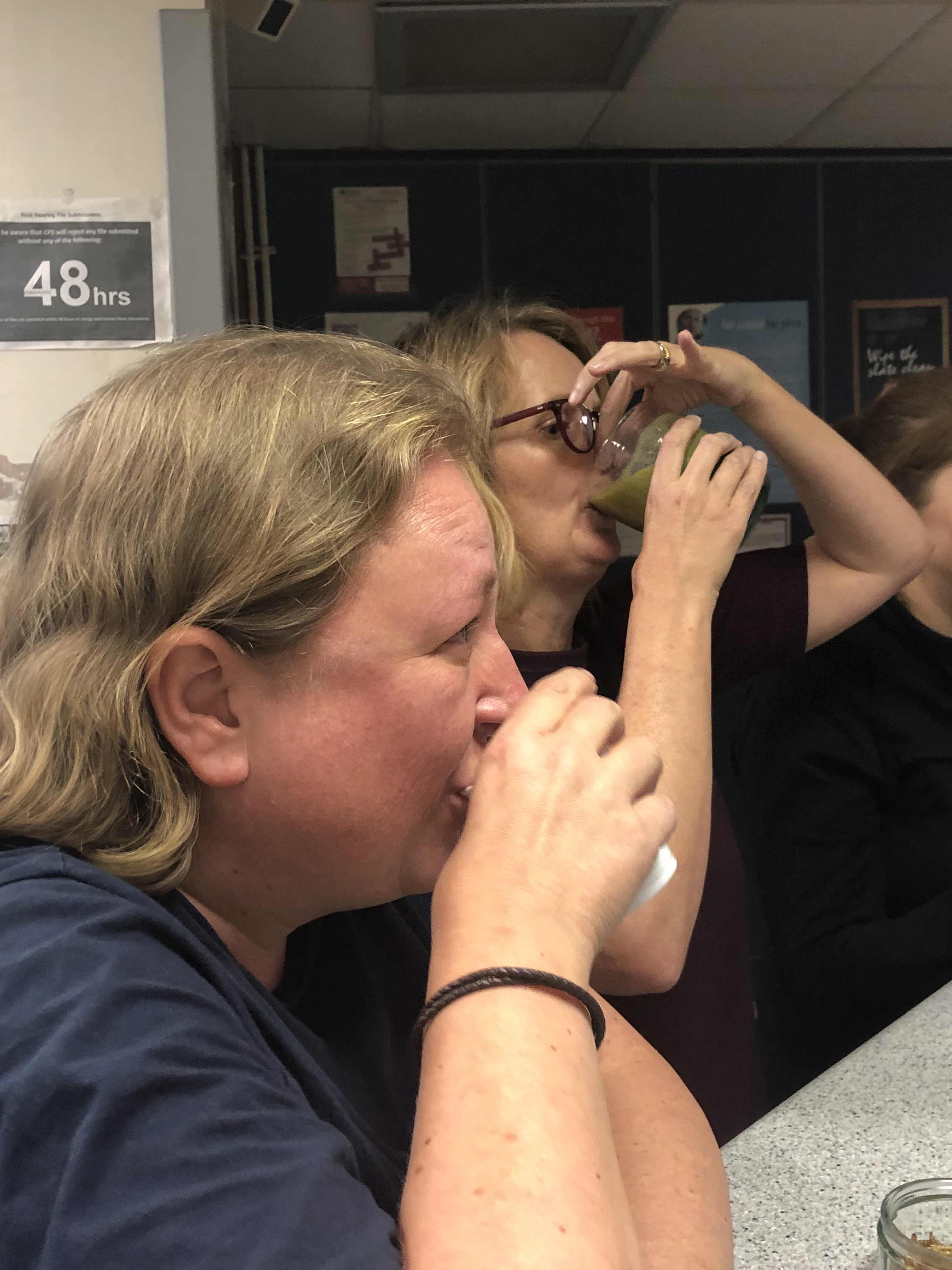 Two people are taking part in a 'gross' challenge, one person is eating dry worms and the other is holding her nose while drinking a gross smoothie