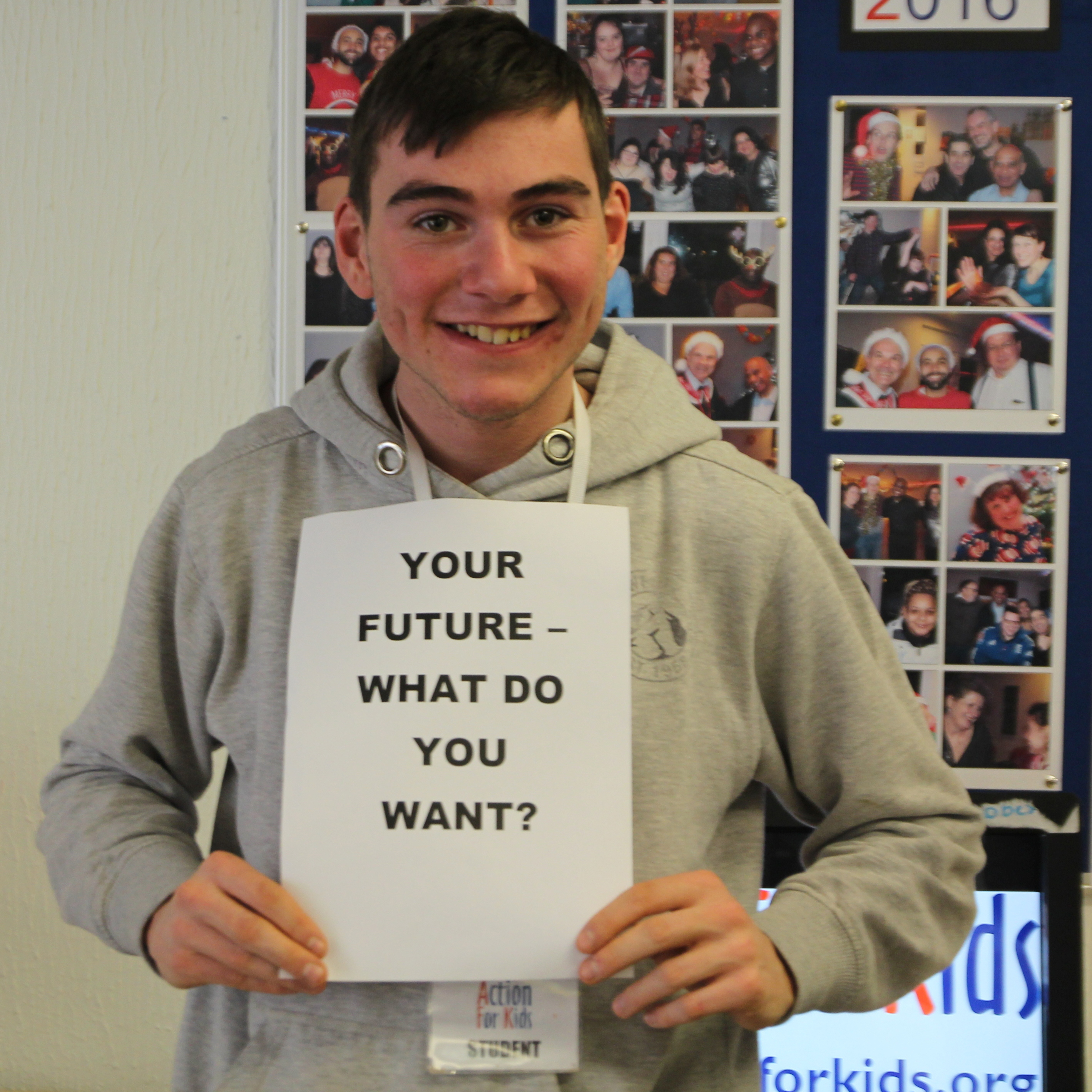 a person is smiling at camera holding a sign that says "Your future, what do you want?"