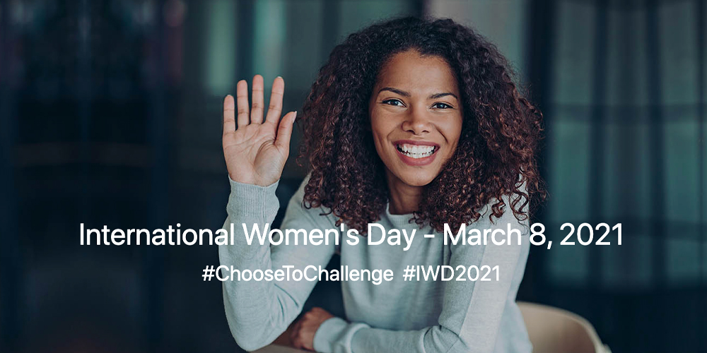 Woman of colour holding her hand up and smiling; text overlaid says "International Women's Day 2021, Choose to Challenge"