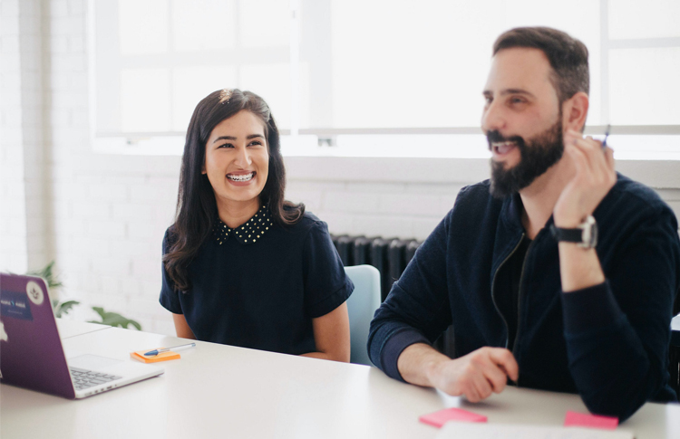 Smiling woman and man at an office table talking